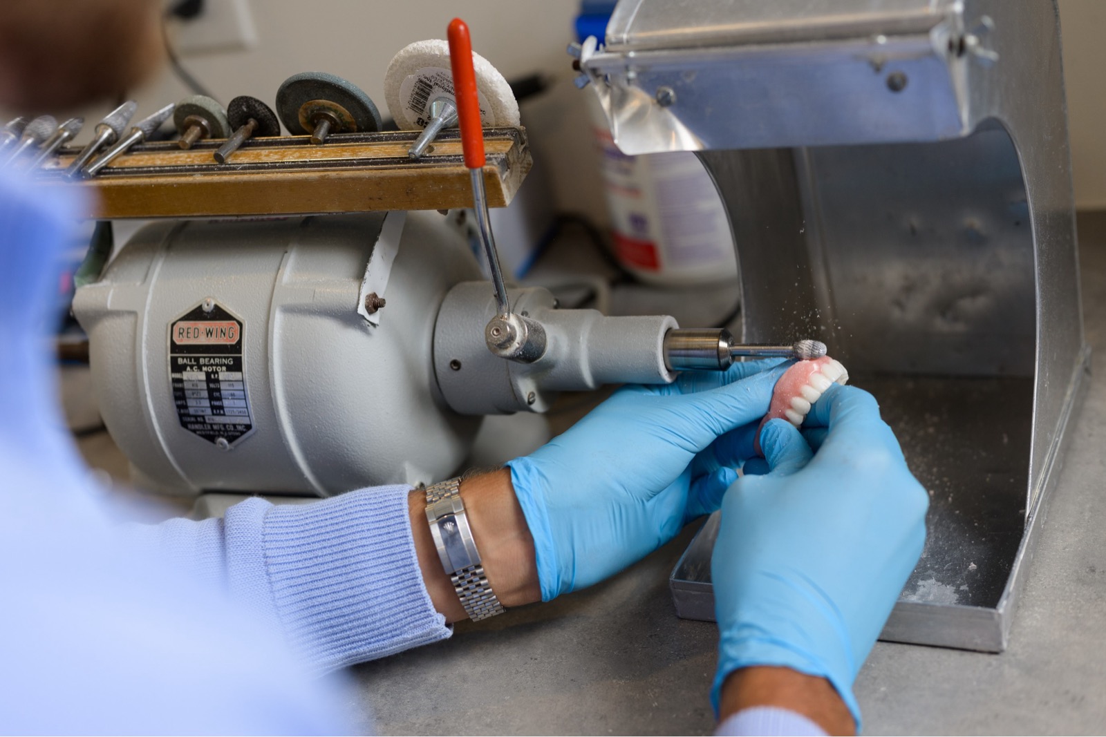 Denturist grinding dentures for a bitter fit